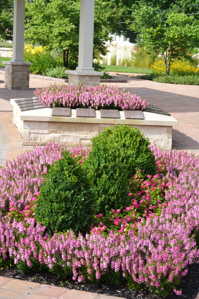 large stone planter with flowers beside a pergola